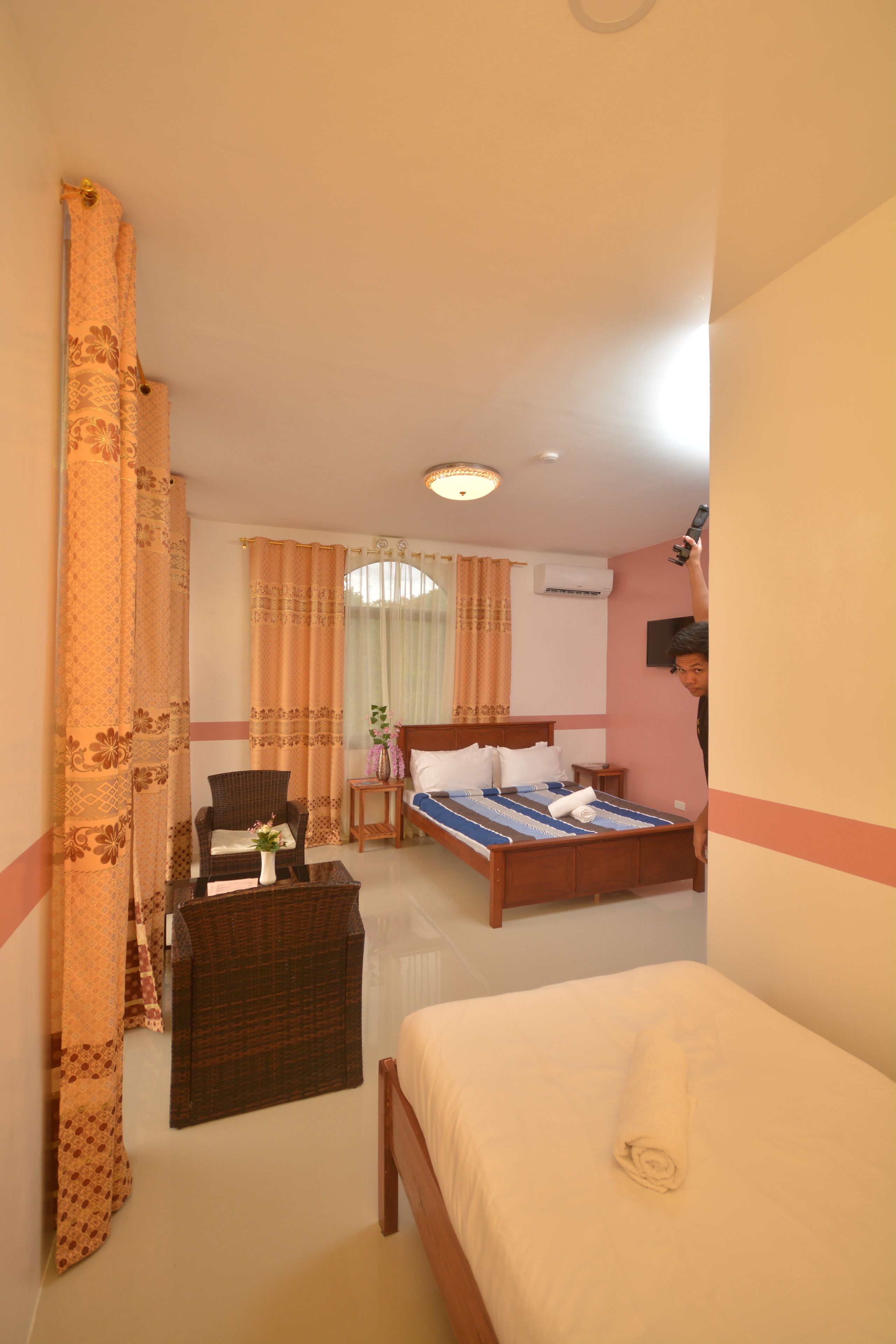 A hotel room with a bed, a chair, a small table, and a window with curtains.