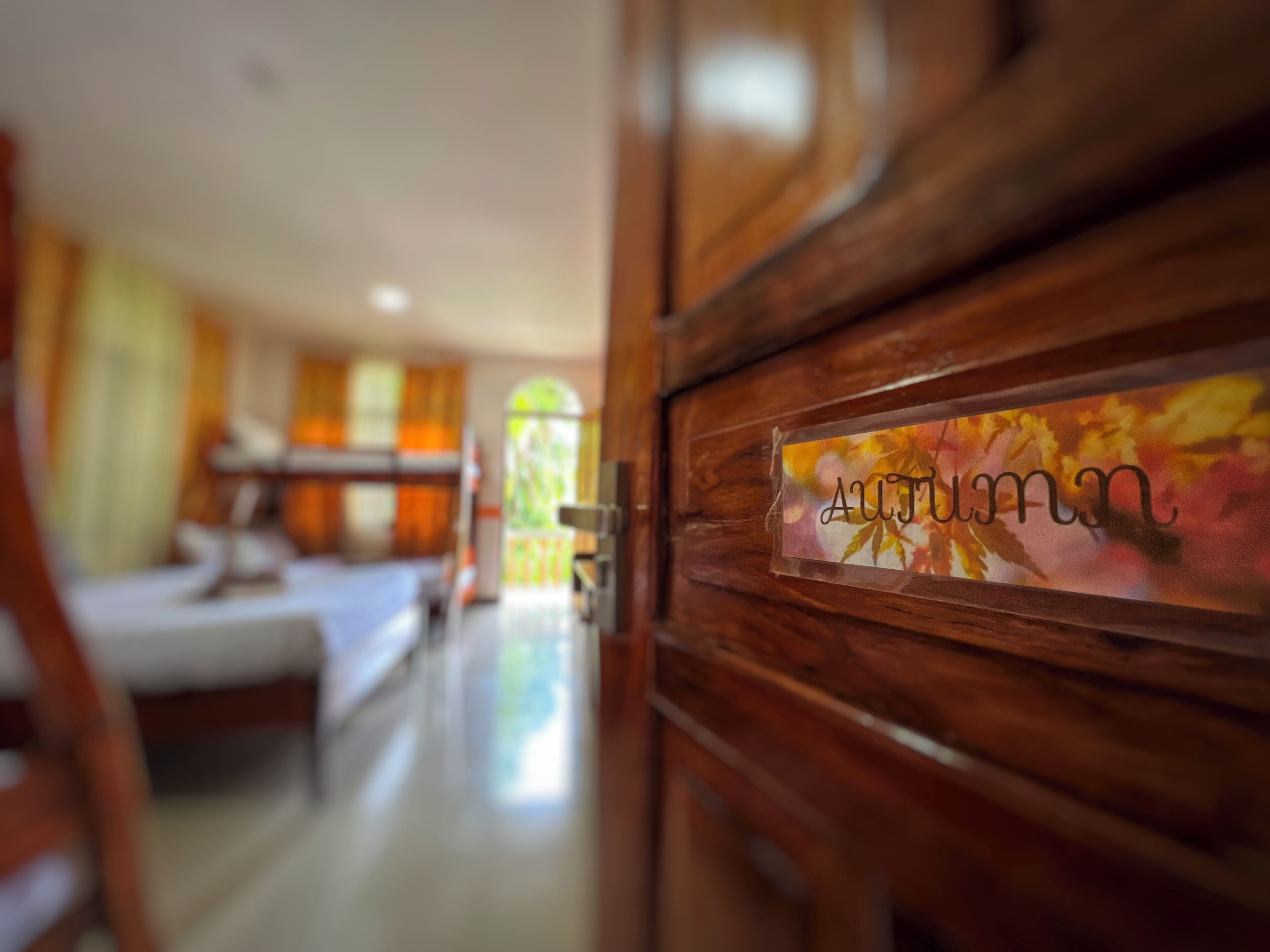 A hotel room with a wooden door, a bed, a desk, and a window.
