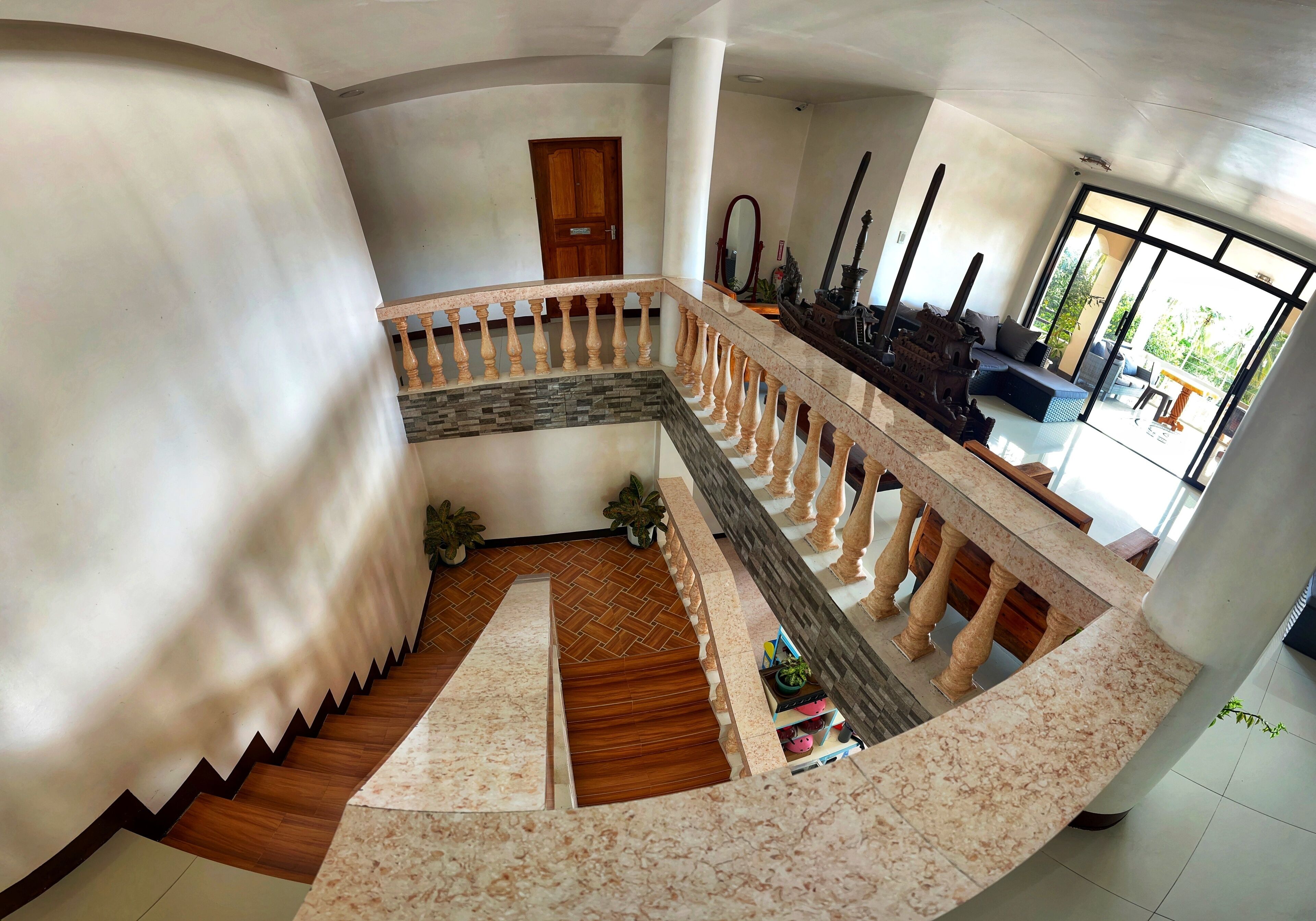 Un interior espacioso con una escalera curva, una puerta de madera y una zona de estar con vistas al exterior.