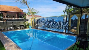 A swimming pool with a tiled edge, surrounded by artificial grass and a mural with the text "The Summerville Tourist Inn". - White Summerville Tourist Inn (Busuanga)