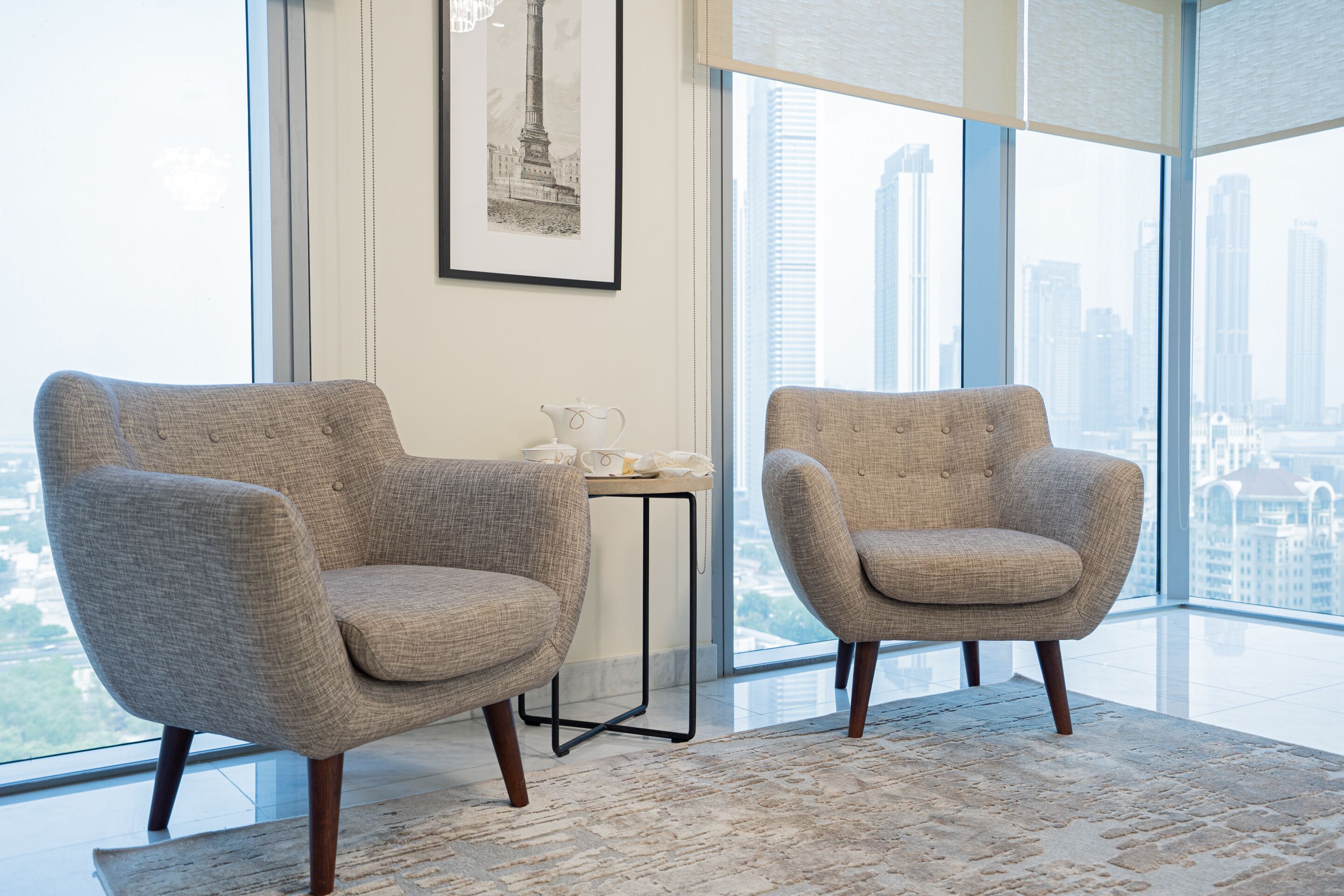 Two armchairs, a small table with a teapot, and a framed picture on the wall.