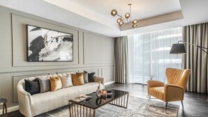 A modern living room with a sofa, armchair, coffee table, and artwork on the wall.