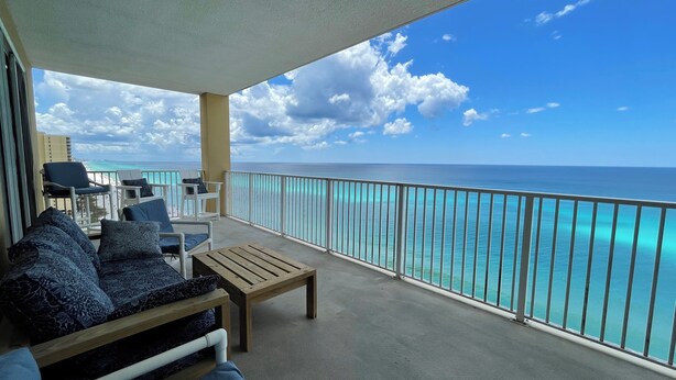 Un balcón con vista al océano, amueblado con un sofá, sillas y una mesa.