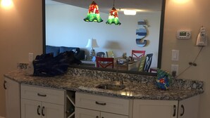 A kitchen with a granite countertop, white cabinets, a stainless steel sink, and two hanging pendant lights. - Serene Oceanfront Getaway Cherry Grove (North Myrtle Beach)3BR (North Myrtle Beach)