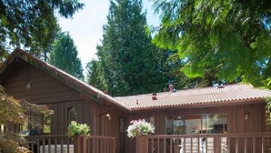 A wooden cabin with a porch, surrounded by trees. - Capilano Forest Little House (District of North Vancouver)