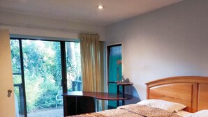 A bedroom with a bed, a desk, and a view of the outdoors. - Capilano Forest Little House (District of North Vancouver)