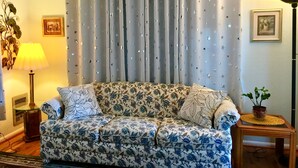Una sala de estar con un sofá estampado de flores, una lámpara y un cuadro en la pared.
