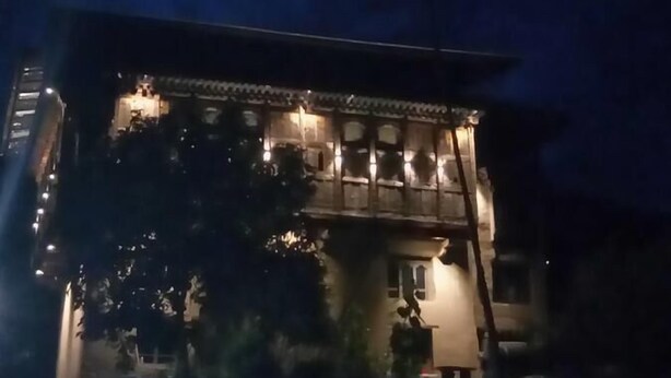 A multi-story building with illuminated windows and a balcony.