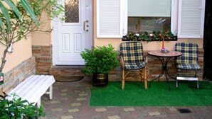 A small patio area with a white door, two wicker chairs, a small table, and a bench. - Apartment in Zagreb with Terrace, Air condition, WIFI, Washing machine (3798-1) (Zagreb)