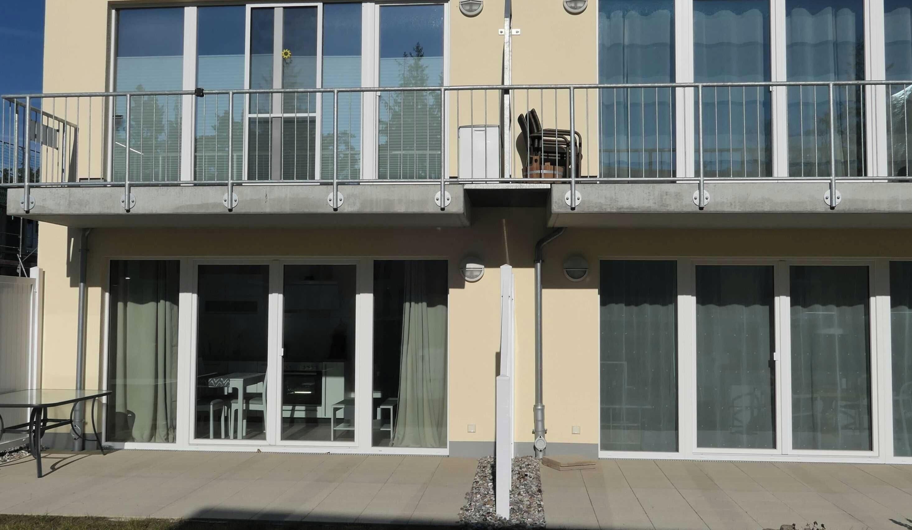 Un edificio moderno con techo plano, ventanas amplias y un balcón con barandillas.