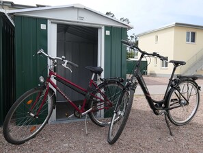 Two bicycles parked outside a building with a green door and a white garage door.