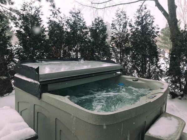 Un bain à remous installé à l’extérieur, dans un décor enneigé.