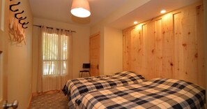Relax in a cozy room with a large bed, chair, and natural light pouring in through sheer curtains.