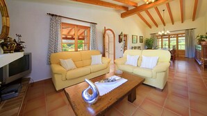 A spacious living room with two yellow sofas, a wooden coffee table, and a television.