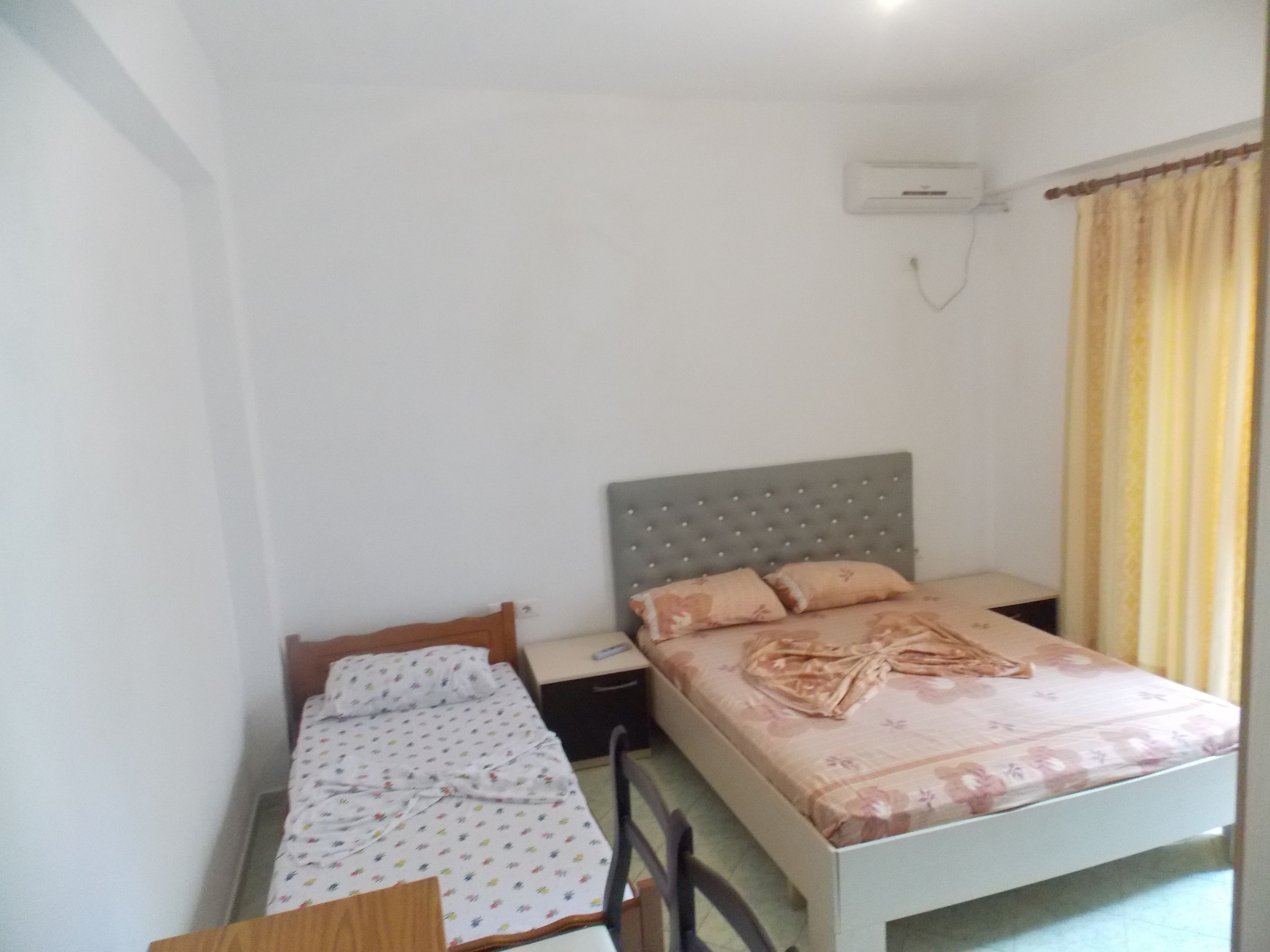Une chambre avec un lit simple, une table de chevet, une chaise et une petite table.