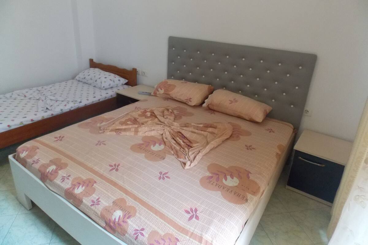 Ein Schlafzimmer mit einem großen Bett, einem kleineren Bett und einem Nachttisch.