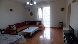 Una sala de estar con sofá, mesa de comedor y televisor.