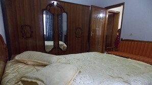 Un dormitorio con una cama grande, un armario de madera y un espejo.