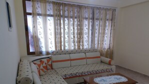 Una sala de estar con un sofá, una mesa de centro y cortinas.