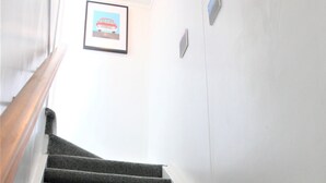 A carpeted staircase with a handrail on the left, white walls, and a framed picture on the wall. - Lakeside apartment with boat ramp & jetties (Koutu)