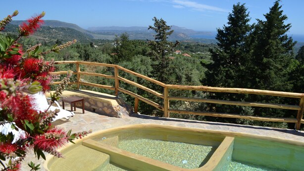 Ein Pool mit Holzterrasse und Steintreppe, umgeben von viel Grün und einer schönen Aussicht.