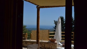 Eine Terrasse mit Steinmauer, Holzmöbeln und Blick auf das Meer.