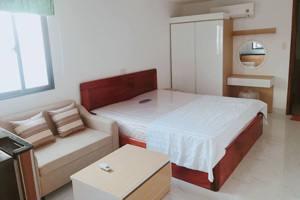 Un dormitorio con cama, mesita de noche, armario y escritorio pequeño.
