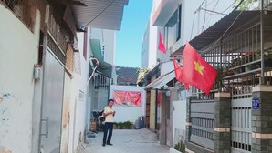 Un estrecho callejón flanqueado por edificios, con una persona de pie en el centro y banderas colgando de las fachadas.