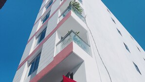 Un edificio alto y blanco con varios balcones y una bandera roja.