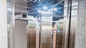 Un ascensor con puertas de vidrio reflectante, barandales metálicos y un diseño de techo moderno.