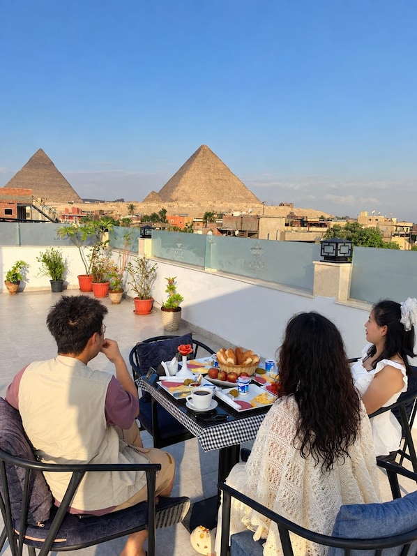 Terraza en la azotea con una mesa dispuesta para comer, con vista a las pirámides.