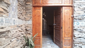 A wooden door with intricate carvings, leading into a room with a stone wall and patterned tiles. - Arabian Nights Pyramids Guesthouse (Giza)