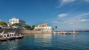 A coastal town with a marina, stone buildings, and a clear blue sky. - Porto Vecchio Luxury Suites (Spetses)