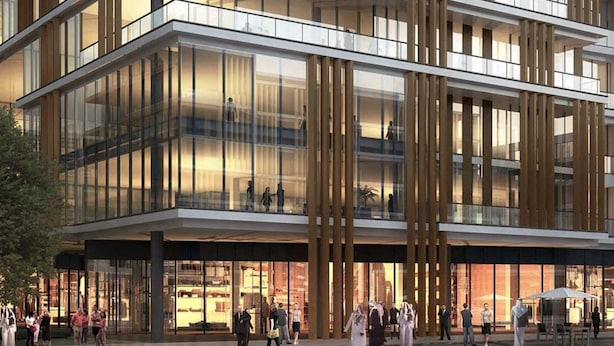 Ett modernt hotell med flera våningar, stora glasfönster, uteservering och en framträdande entré.