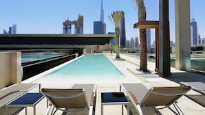 Ett poolområde på taket med solstolar och utsikt över Burj Khalifa.