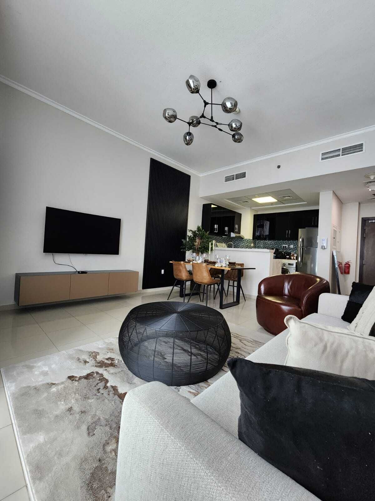 A modern living room with a sofa, a coffee table, and a dining area with chairs.