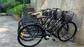 A row of bicycles parked against a stone wall on a paved path.