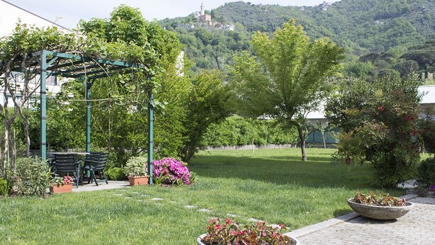 Un jardin agrémenté d’une pergola, d’un espace salon extérieur et de parterres de fleurs.