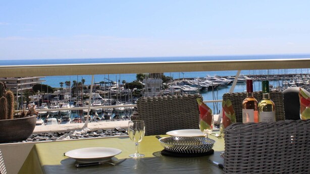 A table set for dining with a view of a marina and boats.