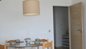 A dining area with a round table, four chairs, and a hanging light fixture.