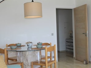 Uma sala de jantar com uma mesa redonda, quatro cadeiras e um lustre.