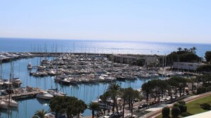 A marina with numerous boats docked, surrounded by greenery and a clear sky.