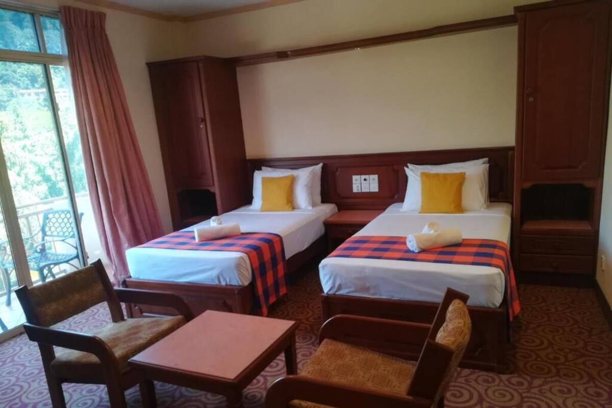 Una habitación de hotel con dos camas, una mesa y dos sillas.