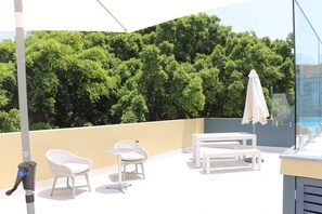 Relax on the shaded outdoor space with a comfortable set of wicker chairs and a table.