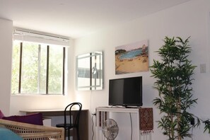 Relax in this cozy living space with a large window, flat-screen TV, and comfortable wicker sofa.