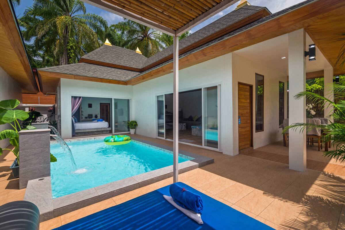 Une maison moderne dotée d’une piscine, d’un patio couvert et d’une grande fenêtre donnant sur la piscine.