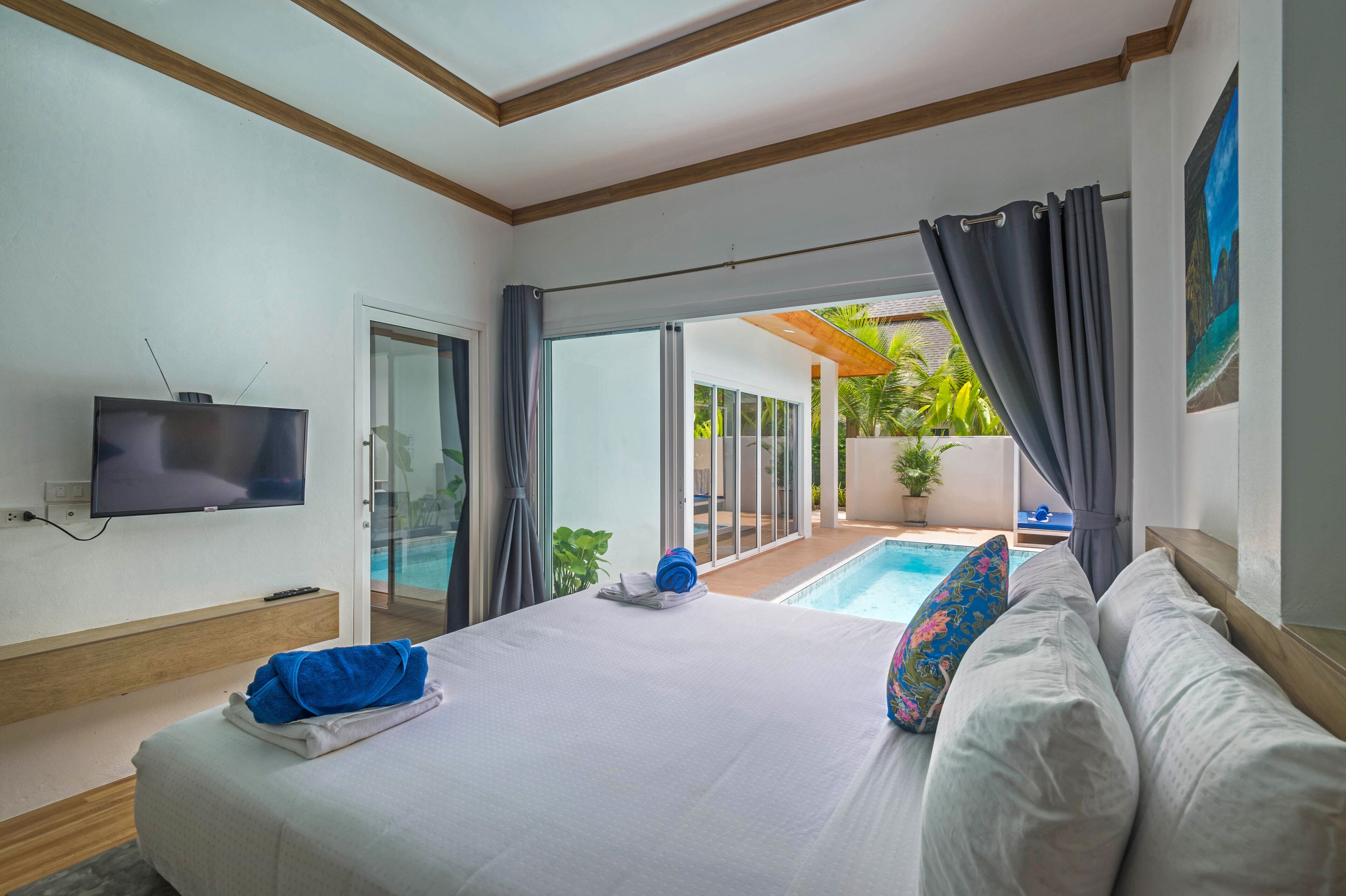 Habitación de hotel con cama, televisor, vista a la piscina y puerta corrediza de vidrio.