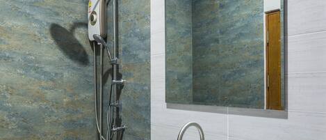 Un baño moderno con un lavamanos grande de color blanco, un cabezal de ducha de mano y un espejo montado en la pared.