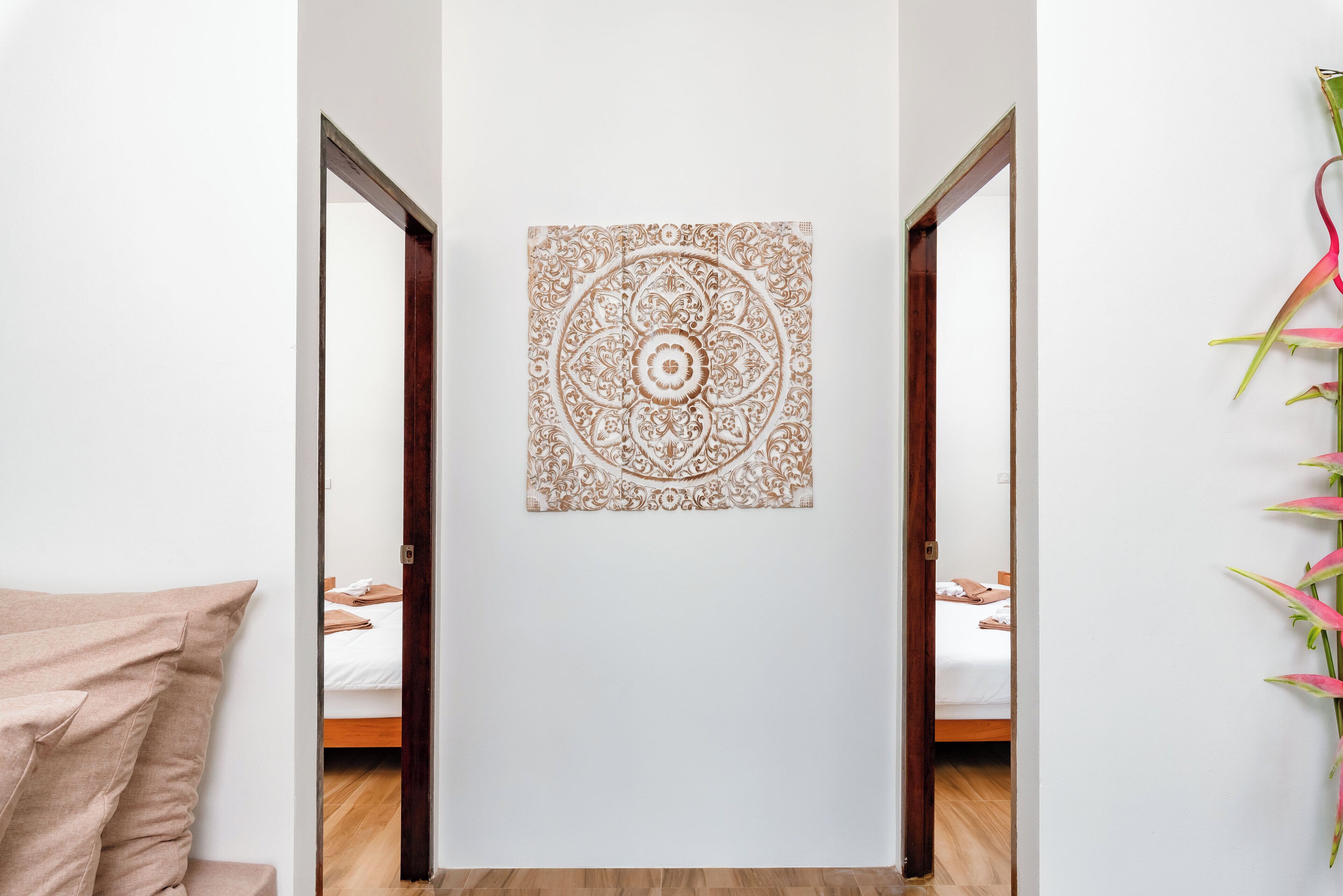 A room with a bed, a wall-mounted decorative panel, and a door leading to another room.