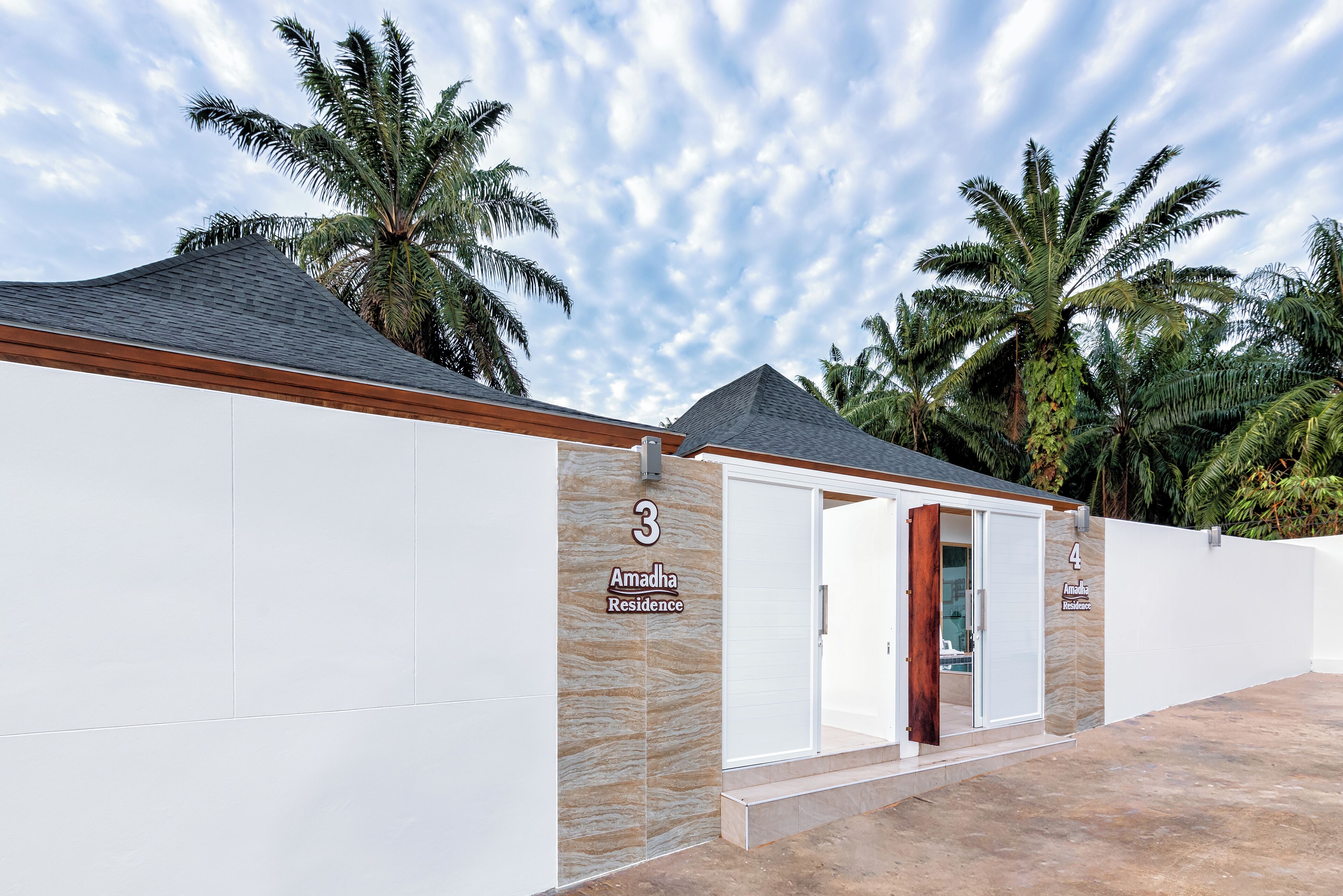 A modern residential building with numbered units, palm trees, and a clear sky.